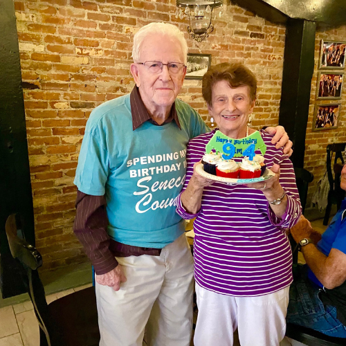 elderly couple holding 94th birthday cake